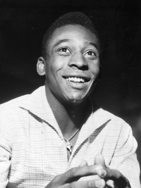 Retrato em preto e branco de Pelé sorrindo, com camisa clara.