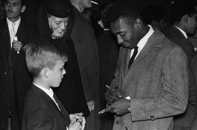 Pelé cercado de pessoas, distribuindo autógrafos.